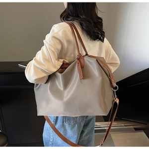 Detail of taupe nylon tote bag featuring brown leather straps and adjustable shoulder strap