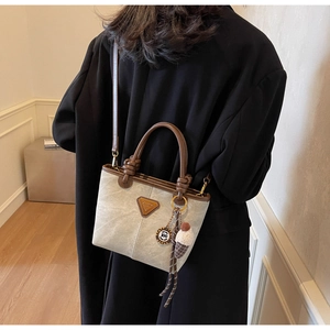 Detailed shot of canvas tote bag with contrast leather handles and triangle logo plaque