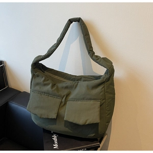 Detail of army green puffer tote bag featuring two front flap pockets and soft nylon texture