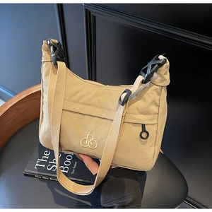 Dettaglio della borsa dumpling in nylon kaki con ricamo bianco e fibbia a scatto rapido