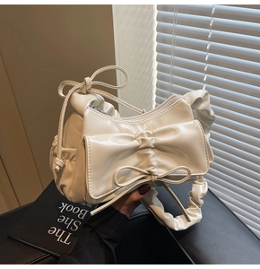 Detail of creamy white ruched shoulder bag with large decorative 3D bow design