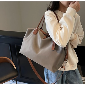 Detail of khaki nylon tote bag with brown leather handles and removable shoulder strap