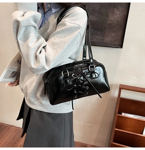Detail der schwarzen Lackleder-Boston-Tasche mit silbernen Beschlägen und Schnürdesign