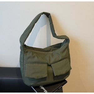 Detail of army green padded puffer crossbody bag with large front flap pockets on a chair