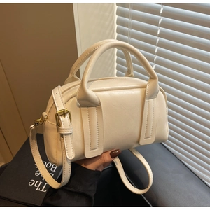 Gros plan du sac Boston crème avec texture en similicuir fin et détails en métal doré chic