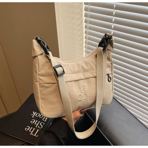 Dettaglio macro della borsa a tracolla in nylon beige con ricamo e spallina larga