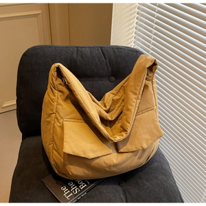 Detail of light brown quilted tote bag with large front pockets on a corduroy chair