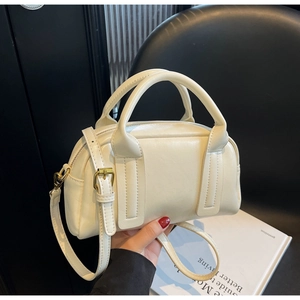 Gros plan du sac Boston crème avec texture en cuir fin et poignées élégantes