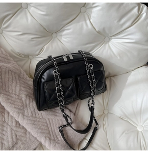 Detail of black quilted leather pillow bag featuring dual front pockets and silver chain strap