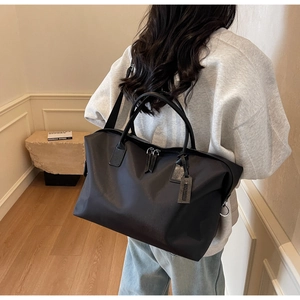 Rear view of model wearing a large black nylon travel tote bag with durable handles