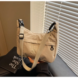 Dettaglio della borsa dumpling in nylon beige con tracolla regolabile e logo ricamato