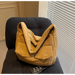 Detail of ginger yellow large capacity tote bag with dual front pockets on a black chair