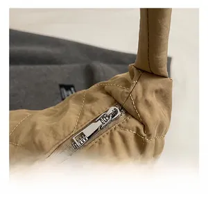 Detailed close-up of the silver metal zipper and quilted nylon fabric on a khaki tote bag