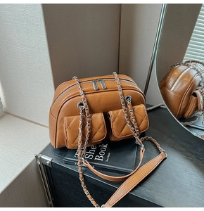 Close-up of caramel quilted crossbody bag with multi-zipper detail and chain strap