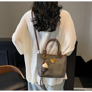 Detail of dark grey tote bag with brown leather handles worn over the shoulder