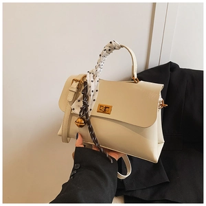 Detail of cream shoulder bag featuring gold twist lock and polka dot scarf handle