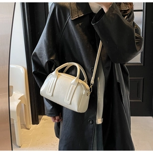 Détails de texture du sac Boston blanc crème avec bandoulière et fermeture éclair en métal