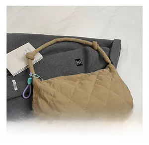 Detail showing khaki quilted shoulder bag with knotted rope handle and colorful charm