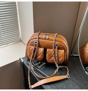 Detail of vintage caramel brown quilted pillow bag with silver chain strap on a wooden desk
