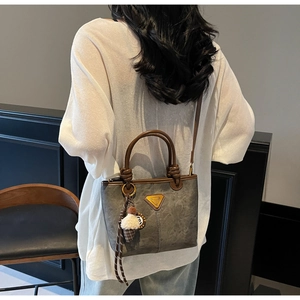 Woman wearing a grey textured tote bag with brown handles and ice cream charm