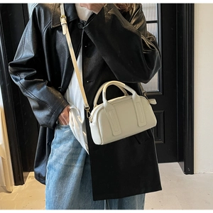 Détail du sac Boston crème montrant la texture cuir litchi et la bandoulière