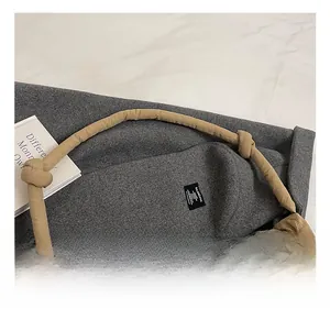 Close-up of khaki quilted shoulder bag featuring soft knotted strap and braided cord charm