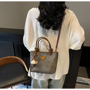 Detail of grey bucket bag showing vintage triangle plaque and cute plush keychain