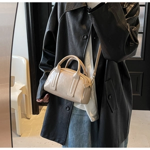 Détails de ce sac Boston beige montrant la texture du cuir et les boucles en métal doré