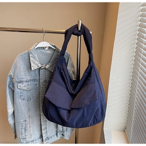 Detail of navy blue nylon tote bag with two front pockets on a metal hanger