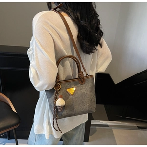 Detail of grey marble pattern tote with brown leather straps and gold triangle plaque