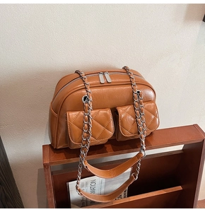 Detail of vintage brown quilted pillow bag with dual front pockets on a wooden shelf