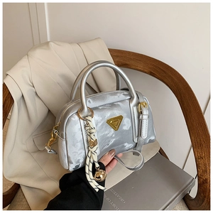 Détail du sac oreiller en satin argenté avec plaque dorée et pendentif clochette