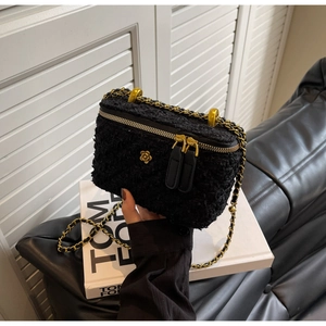 Close-up of black tweed camera bag with golden flower logo and woven metal chain strap
