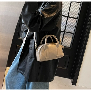 Détail du sac Boston beige porté, avec bandoulière réglable et ferrures dorées chic