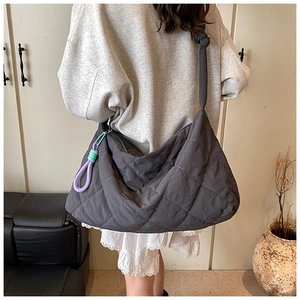 Detail of grey quilted tote bag with knotted shoulder strap and colorful rope accessory