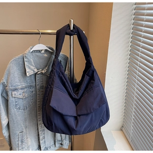 Detail of navy nylon tote bag with double flap pockets and wide shoulder strap