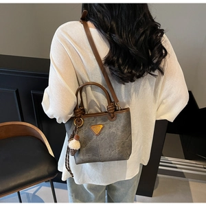 Detail of vintage tote bag with grey textured finish and cute plush charm accessory