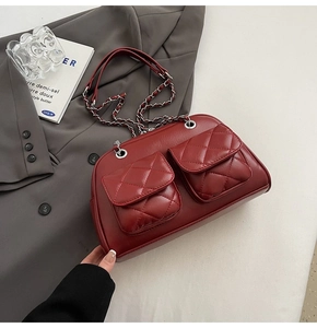 Macro detail of red quilted leather texture and silver chain strap on crossbody bag