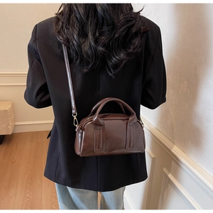 Détail du sac Boston marron foncé avec ferrures dorées et bandoulière réglable pratique