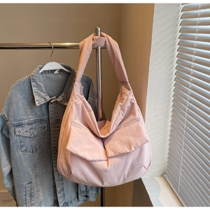Detail of light pink quilted puffer tote bag with dual front pockets and soft texture
