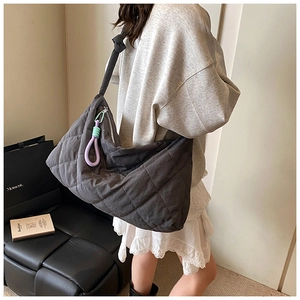 Detail of dark grey quilted crescent tote bag worn as a shoulder bag in lifestyle setting