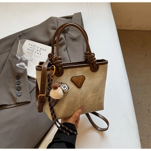 Detail of beige suede tote bag with leather trim, ice cream charm and wrapped handle