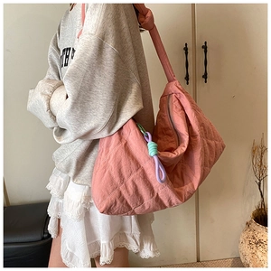 Detailed shot of pink quilted hobo bag with knotted strap and braided tassel accessory