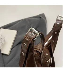 Detail of adjustable glossy brown leather shoulder strap with silver eyelet buckles