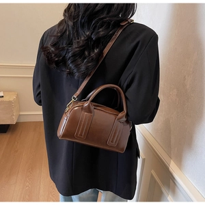 Détail du sac Boston marron foncé avec finition brillante et ferrures dorées