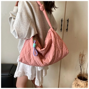 Pink quilted tote bag with knot detail and woven strap accessory on model shoulder