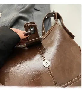 Close-up of glossy brown oil wax leather bag with silver magnetic metal buckle