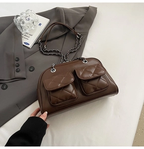 Detail of dark brown quilted pillow bag showing dual front pockets and metal chain strap