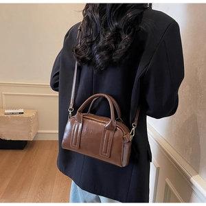 Détail du sac Boston marron vintage porté en bandoulière avec finitions dorées chic