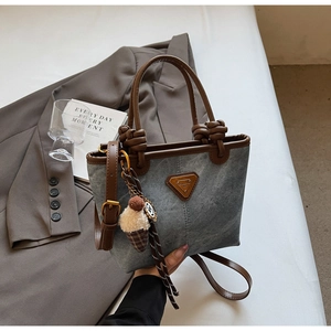 Detail of vintage gray denim tote bag featuring brown leather knotted handles and ice cream charm